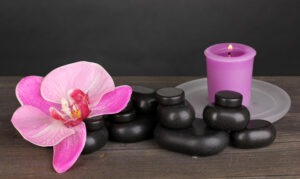 spa-stones-with-orchid-flower-candle-wooden-table-grey-background